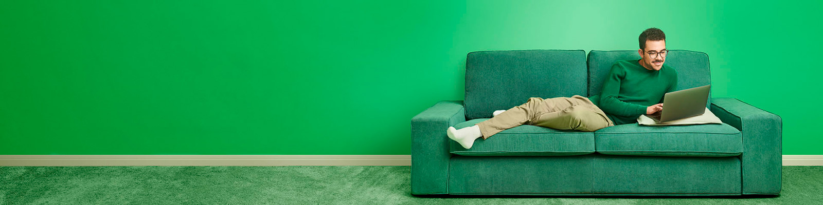 young man on green couch with laptop
