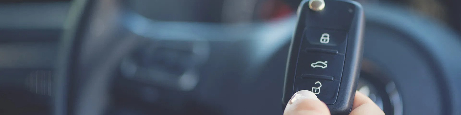 close up of car key in front of steering wheel