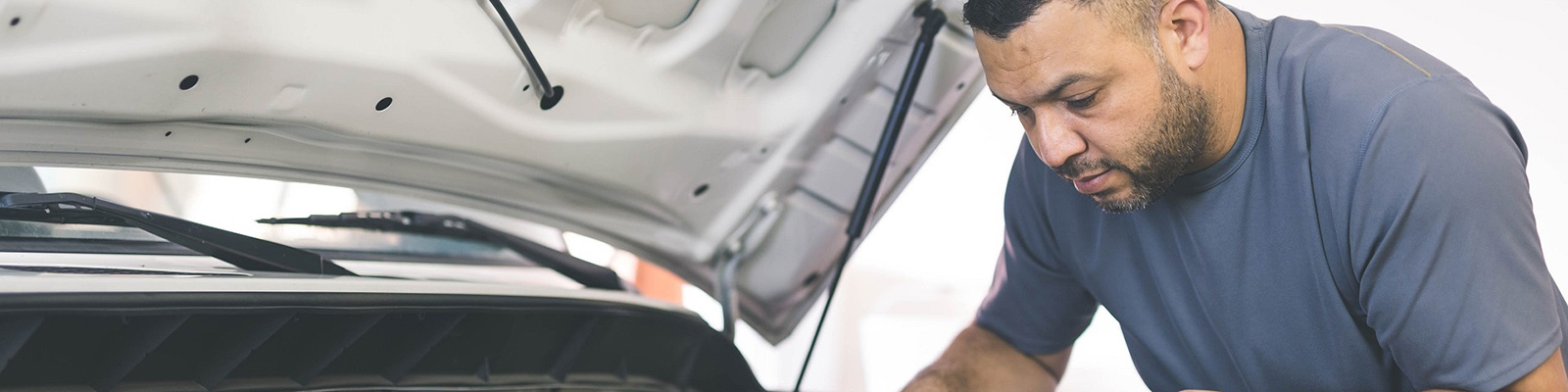 man looking into open car bonnet