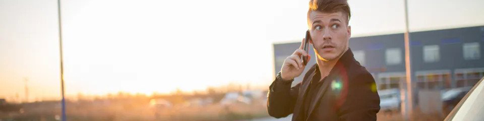 man on phone standing next to car