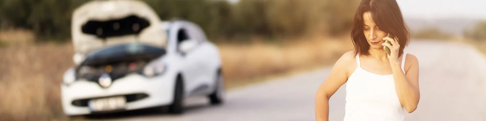 woman standing next to broken down car