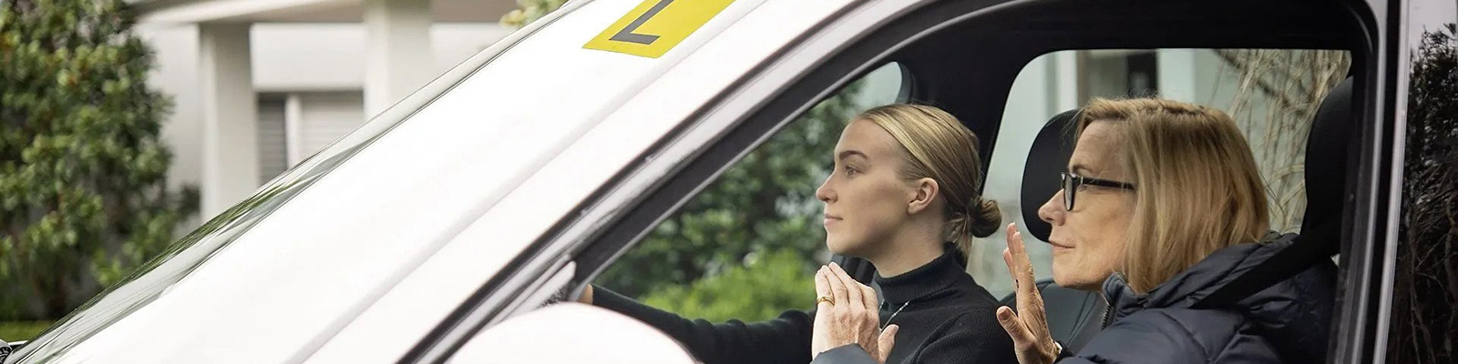 young woman driving car with older woman