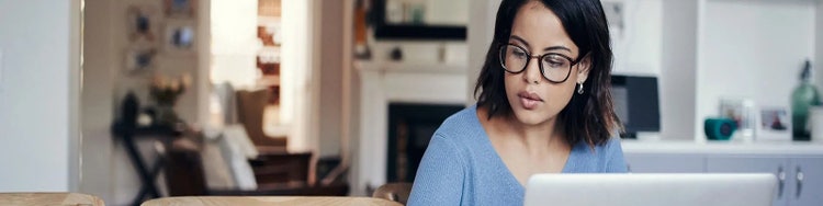 Woman calculating budget on her laptop in the kitchen