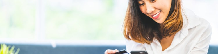Lady checking phone while holding debit card in hand