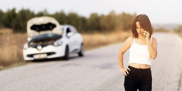Woman standing next to broken down car
