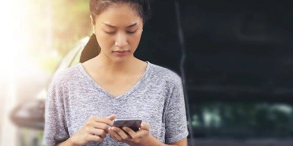 Woman with mobile phone looking stressed after car broken down