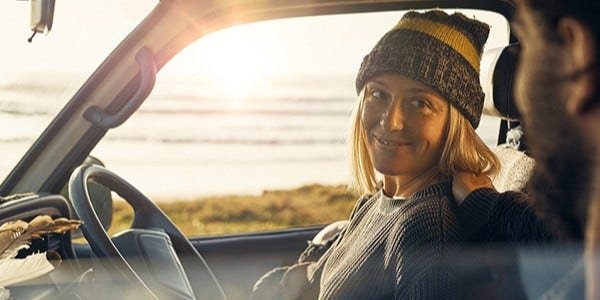 Smiling woman and man in parked car by beach