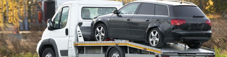 Black station wagon sitting on flatbed tow truck