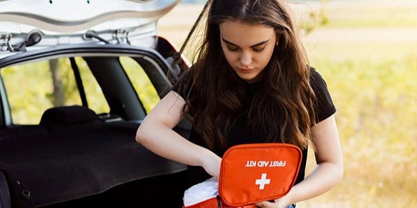 Woman with first aid kit outside car